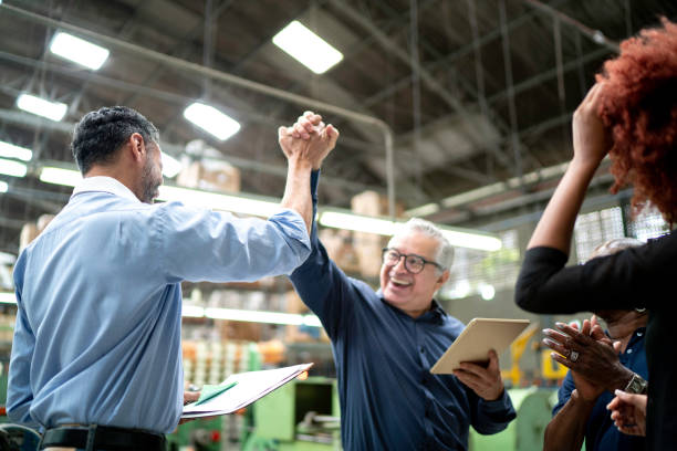 A team celebrating a success in a warehouse, high-fiving each other.