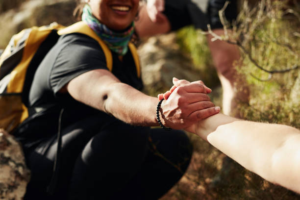 One person helping another up a rock, symbolizing empowerment.
