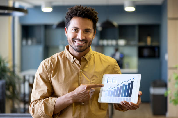 A smiling man pointing to a tablet showing a graph with an upward trend, symbolizing improved paid growth efficiency.